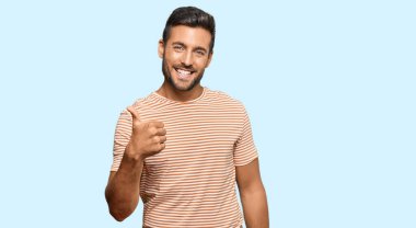 Sıradan kıyafetler giyen yakışıklı İspanyol bir adam. Elle mutlu bir jest yapıyor. Kameraya bakıp başarıyı gösteren ifade. 