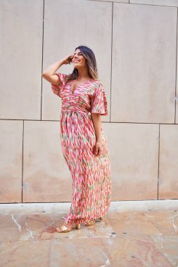 Güzel, genç bir kadın, şık kıyafetler giyip sokakta yürüyor.