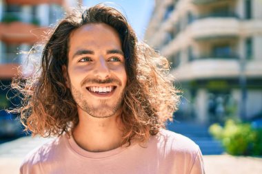 Genç İspanyol adam şehirde mutlu gülümsüyor..