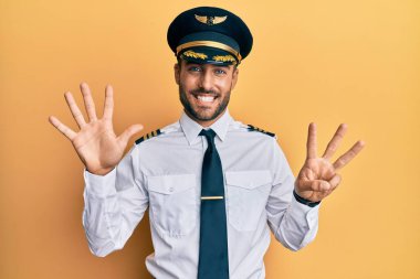 Yakışıklı İspanyol pilot üniforması giyiyor. Sekiz numaralı parmaklarıyla işaret ediyor ve gülümsüyor. Kendinden emin ve mutlu.. 