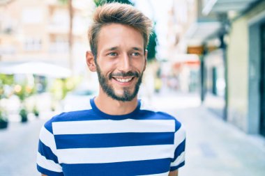 Sakallı yakışıklı beyaz adam, dışarıda mutlu bir şekilde gülümsüyor.