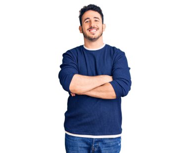 Gündelik kıyafetler giyen, kollarını kavuşturup kameraya gülümseyen genç İspanyol adam. pozitif kişi. 