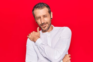 Genç, yakışıklı, günlük kıyafetler giyen, kendine sarılan mutlu ve pozitif, kendinden emin gülümseyen bir adam. Sevgi ve özgüven. 