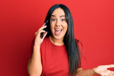 Genç ve güzel İspanyol kız akıllı telefonda konuşuyor başarıyı mutlu bir gülümsemeyle kutluyor ve kazanan el kaldırarak ifade ediyor. 