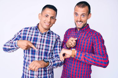 Gündelik giysiler giyen iki genç gay saati izlemek için acele ediyorlar, sabırsızlar ve gecikme yüzünden kızgınlar. 