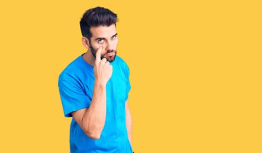 Sakallı, sıradan tişörtlü genç ve yakışıklı bir adam. Gözünü dikip jestini izliyor. Şüpheli bir ifade. 