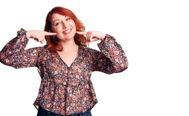 Genç, güzel, kızıl saçlı, sıradan tişörtler giyen neşeli bir şekilde gülümseyen, parmakları ve ağzı olan bir kadın. diş sağlığı kavramı. 