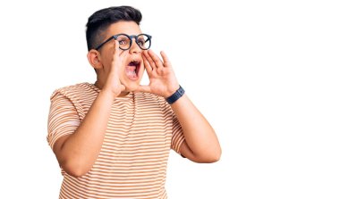 Günlük kıyafetler ve gözlük takan küçük çocuk elleri ağızda bağırarak bağırıyor. 