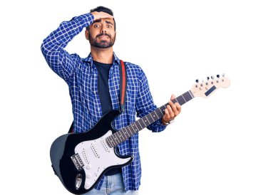 Elektro gitar çalan genç İspanyol adam, gergin ve hayal kırıklığına uğramış, şaşırmış ve sinirli bir yüz ifadesiyle. 