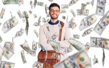Deri çanta giyen, kollarını kavuşturup kameraya gülümseyen genç, yakışıklı İspanyol adam. pozitif kişi.