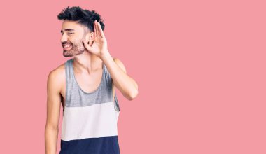 Gündelik kıyafetler giyen, ağzı kulaklarında gülümseyen genç İspanyol bir adam dedikoduları ve dedikoduları dinliyor. Sağırlık kavramı. 