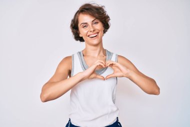 Genç İspanyol kadın spor kıyafetleri giyiyor. Sevgiyle gülümsüyor. Elleriyle kalp sembolü ve şekli gösteriyor. romantik kavram. 