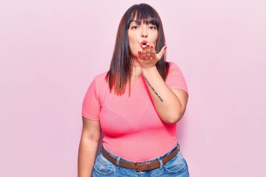 Genç ve cüsseli bir kadın, gündelik giysiler giyip kameraya bakıyor ve havada bir öpücük savuruyor. Güzel ve seksi. aşk ifadesi. 