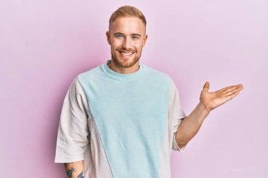 Gündelik kıyafetler giyen, neşeli gülümseyen, el ele tutuşup kameraya bakan beyaz bir genç.. 