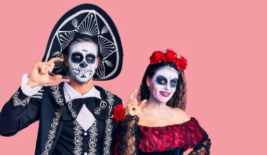 Arka planda Meksika kostümlü genç bir çift gülümsüyor ve el hareketleriyle küçük beden işareti yaparak kameraya bakıyor. ölçüm kavramı. 