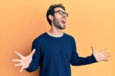 Gündelik kıyafetler giyen, gözlüklü, deli gibi bağıran, sinirli ifadeli ve kollarını kaldırmış genç İspanyol bir adam. hüsran kavramı. 