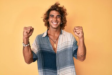 Yaz stili giyinmiş İspanyol genç adam gururla bağırıyor, zaferi kutluyor ve başarıyı kollarını kaldırarak kutluyor. 