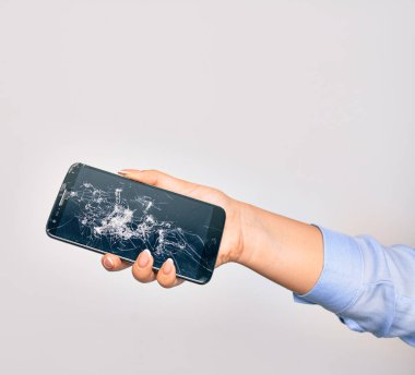 Kırık akıllı telefon tutan beyaz arka planda beyaz ekran görüntüsü olan beyaz bir kadının eli.