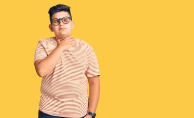 Günlük giysiler giyen, gözlüklü, boynu ağrıyan, boğazı ağrıyan grip, mantar ve enfeksiyon kapmış küçük bir çocuk. 