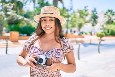 Şehrin caddesinde gezen eski model kamera kullanan genç Latin kadın..