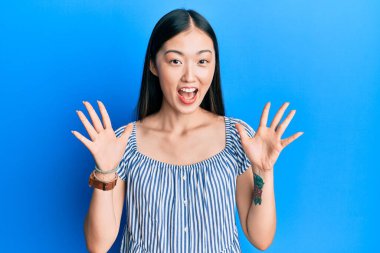 Sıradan çizgili tişört giyen genç Çinli kadın çılgınlığı kutluyor ve kollarını kaldırıp heyecanla haykırarak zafere koşuyor. Kazanan konsept 