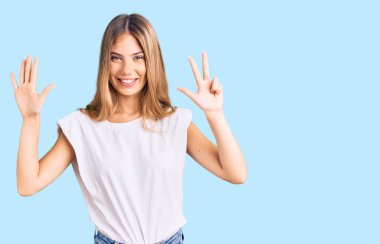 Sarışın, beyaz tişörtlü güzel beyaz kadın 8 numaralı parmaklarıyla gülümseyerek mutlu ve kendinden emin görünüyor.. 