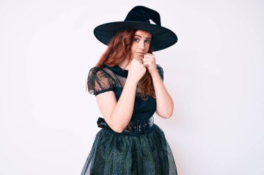 Cadı cadılar bayramı kostümü giymiş genç bir kadın yumruk savunma hareketiyle dövüşmeye hazır kızgın ve üzgün bir yüz, sorundan korkuyor. 