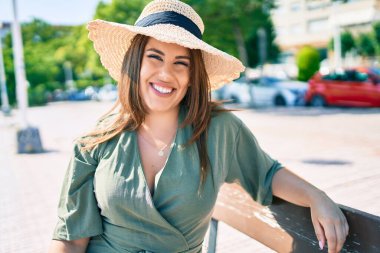 Genç İspanyol kadın tatilde gülümsüyor. Mutlu bir şekilde şehrin sokaklarında bankta oturuyor.