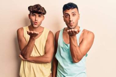 Gündelik giysiler giymiş genç eşcinsel bir çift kameraya bakıyor. Canlı yayında öpüşüyorlar. Güzel ve seksiler. aşk ifadesi. 