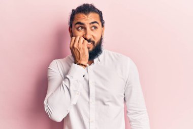 Gündelik kıyafetler giyen genç bir Arap, gergin ve gergin görünüyor. Ağzı tırnak yiyen ellerle. anksiyete. 