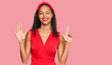 Zarif ve seksi görünümlü genç Afrikalı Amerikalı kız yedinci parmaklarını gösterip işaret ederken kendinden emin ve mutlu gülümsüyor.. 