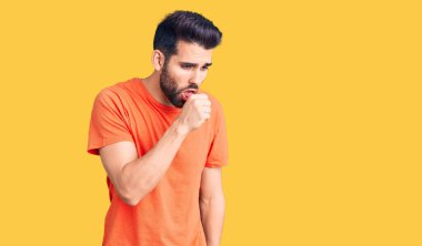 Sakallı, sıradan bir tişört giyen, kendini kötü hisseden ve soğuk algınlığı veya bronşitin belirtisi olarak öksüren genç yakışıklı bir adam. sağlık hizmeti kavramı. 