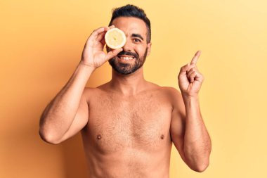 Genç İspanyol adam limonsuz duruyor. Gülümsüyor. Elleri ve parmakları yana doğru uzanıyor. 