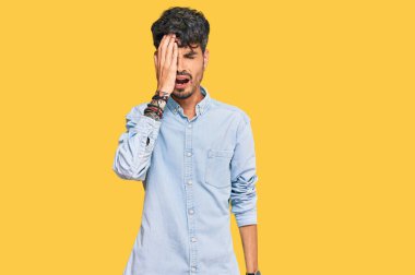 Latin asıllı genç bir adam günlük kıyafetler giyiyor. Yarı yüzünü, göz ve ağzını eliyle kapatmaktan yoruluyor. Yüzüm acıyor.. 