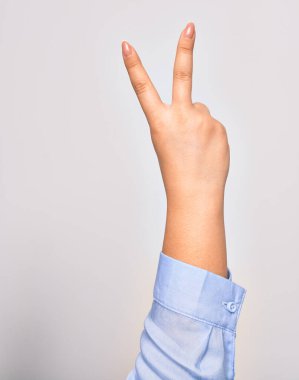 Kafkasyalı genç bir kadın zafer sembolü çiziyor. İki numarayı gösteriyor. Parmakları uzamış, izole beyaz arka planda.