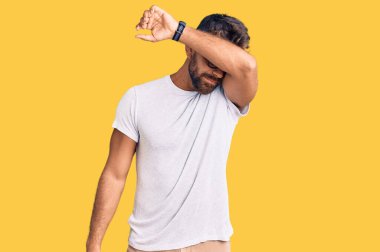 Gündelik kıyafetler giyen ve gözlük takan genç İspanyol adam gözlerini kollarıyla kapatıyor, ciddi ve üzgün görünüyor. Görme, saklama ve reddetme konsepti 