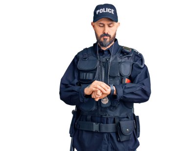 Polis üniforması giyen genç yakışıklı saati kontrol ediyor, rahat ve kendinden emin. 