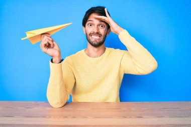 Elinde kağıt uçak tutan yakışıklı İspanyol adam. Eli kanlı, şaşırmış ve sinirli. 