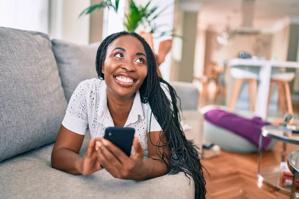 Jovem Afro Americana Sorrindo Feliz Usando Smartphone Deitado Sofá Casa — Fotografia de Stock