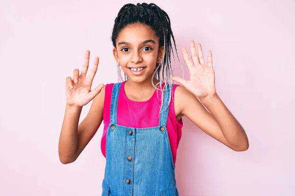 若いですアフリカ系アメリカ人の女の子子供とともにBraids身に着けていますカジュアル服上のピンクの背景表示と指摘指番号8ながら笑顔自信と幸せ — ストック写真