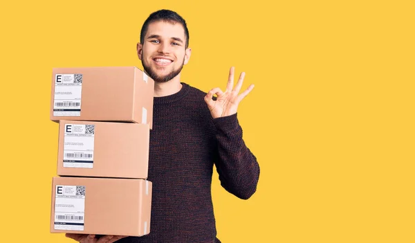 Joven Hombre Guapo Sosteniendo Paquete Entrega Haciendo Signo Bien Con — Foto de Stock