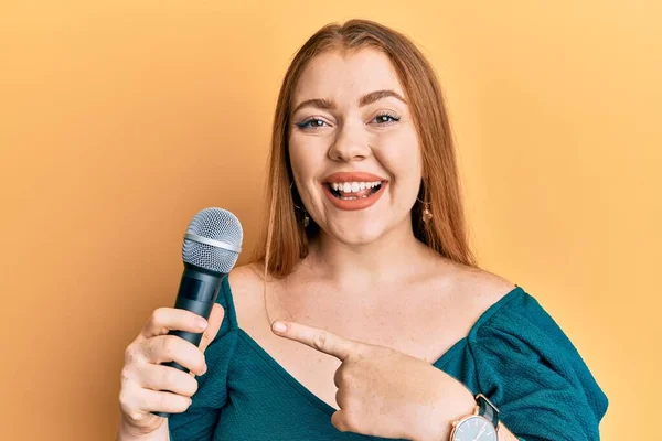 Joven Hermosa Pelirroja Cantando Canción Usando Micrófono Sonriendo Feliz Señalando — Foto de Stock