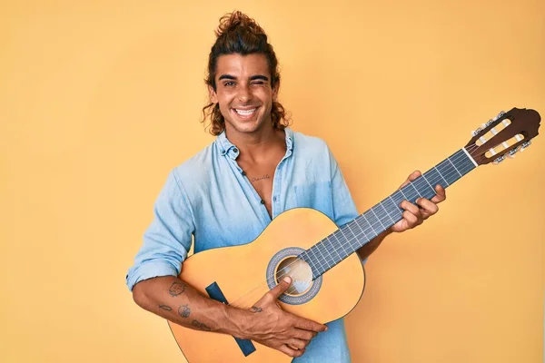 Joven Hombre Hispano Tocando Guitarra Clásica Guiñando Ojo Mirando Cámara —  Fotos de Stock