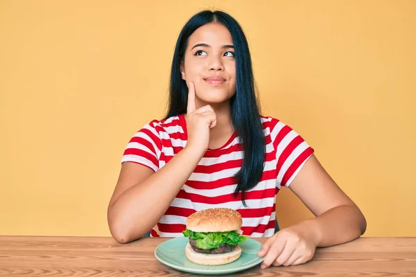 Νεαρή Ασιάτισσα Τρώει Ένα Νόστιμο Κλασικό Burger Σοβαρό Πρόσωπο Σκέφτεται — Φωτογραφία Αρχείου