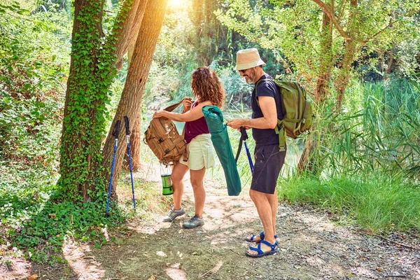 美丽的一对徒步旅行者背着背包在森林里用手杖徒步旅行 — 图库照片