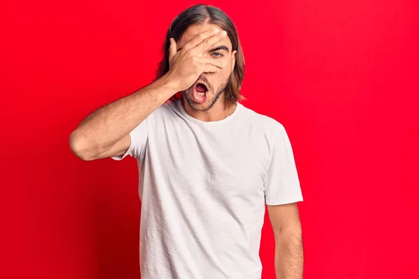 Jovem Homem Bonito Vestindo Roupas Casuais Espreitando Choque Cobrindo Rosto — Fotografia de Stock