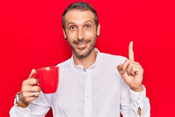 Jovem Homem Bonito Segurando Café Sorrindo Com Uma Ideia Pergunta — Fotografia de Stock