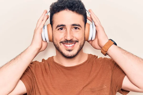 Young Hispanic Man Listening Music Using Headphones Looking Positive Happy — Stock Photo, Image