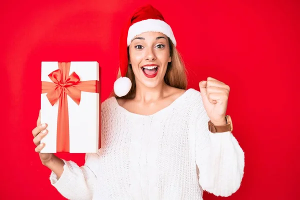 Junge Brünette Frau Trägt Weihnachtsmütze Und Hält Ein Geschenk Schreit — Stockfoto