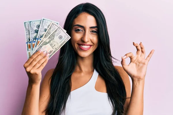 Beautiful Hispanic Woman Holding Dollars Doing Sign Fingers Smiling Friendly — Stock Photo, Image
